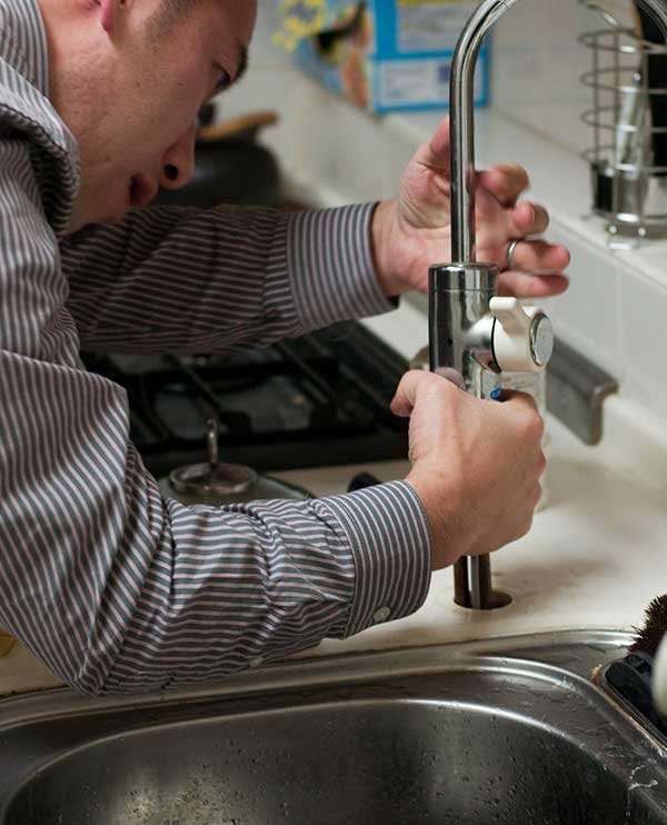 Professional plumber fixing kitchen sink faucet